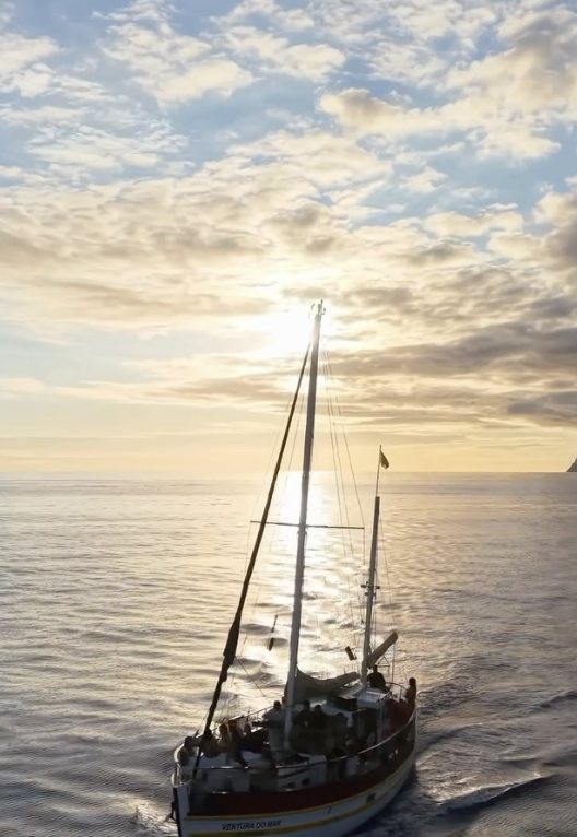 Traditional sailing boat cruising into the sunset off Madeira