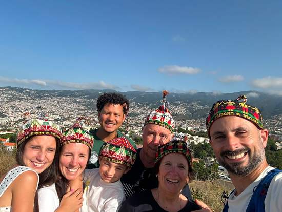 Guests wearing traditional Madeiran hats with Funchal in the background