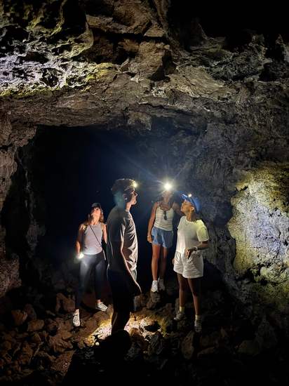 Guests exploring a lava cave with headlamps in Madeira