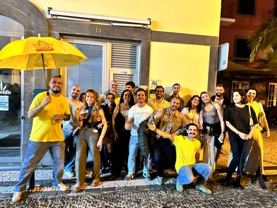 Large pub crawl group under a yellow umbrella in Funchal at night